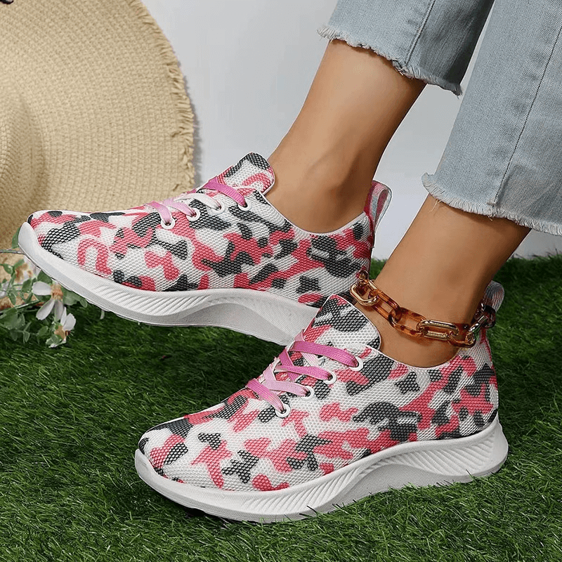 Women's breathable mesh non-slip sports shoes with pink camouflage pattern, lace-up design, and rubber outsole on grass.